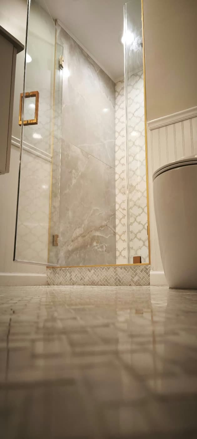 Glass shower with large marble-look tile, an arabesque mosaic accent and gold trim — ProRock Remodeling, Bay Area