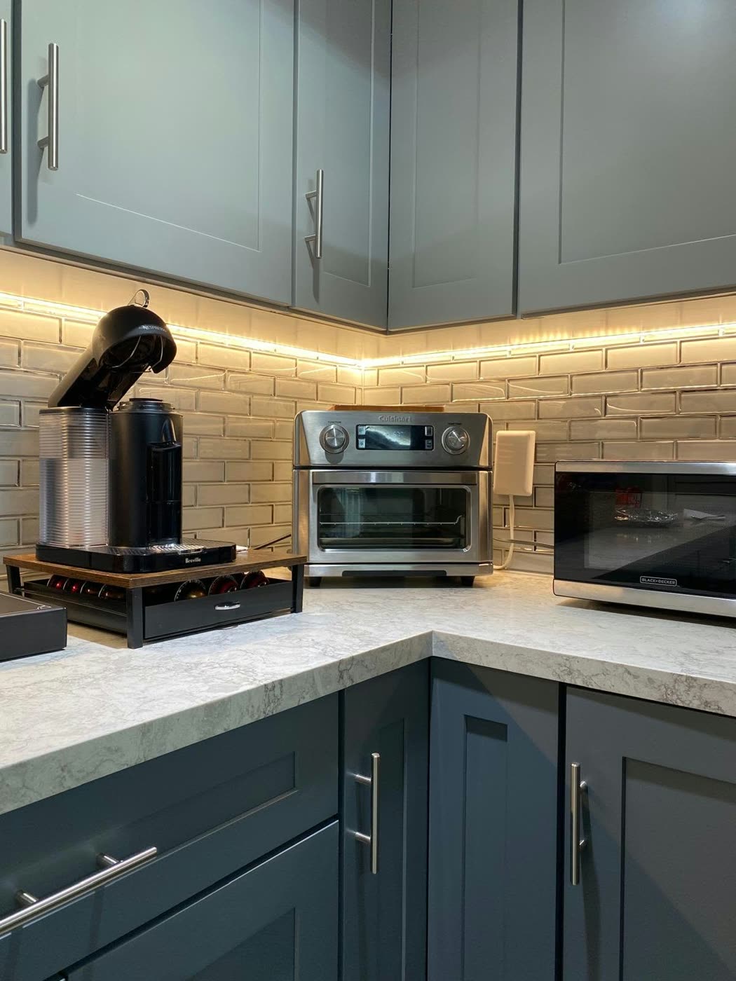 Blue-gray shaker cabinets with LED under-cabinet lighting and a white brick-look backsplash — ProRock Remodeling, Bay Area