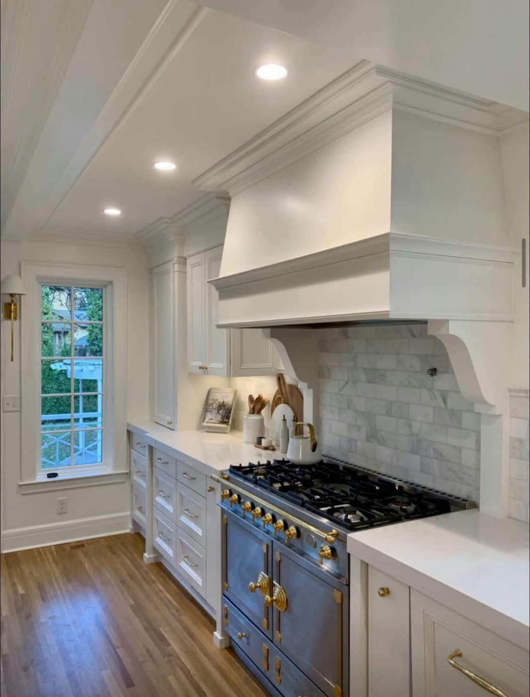 Classic white kitchen with a custom range hood, marble backsplash and a navy and brass range — ProRock Remodeling, Bay Area