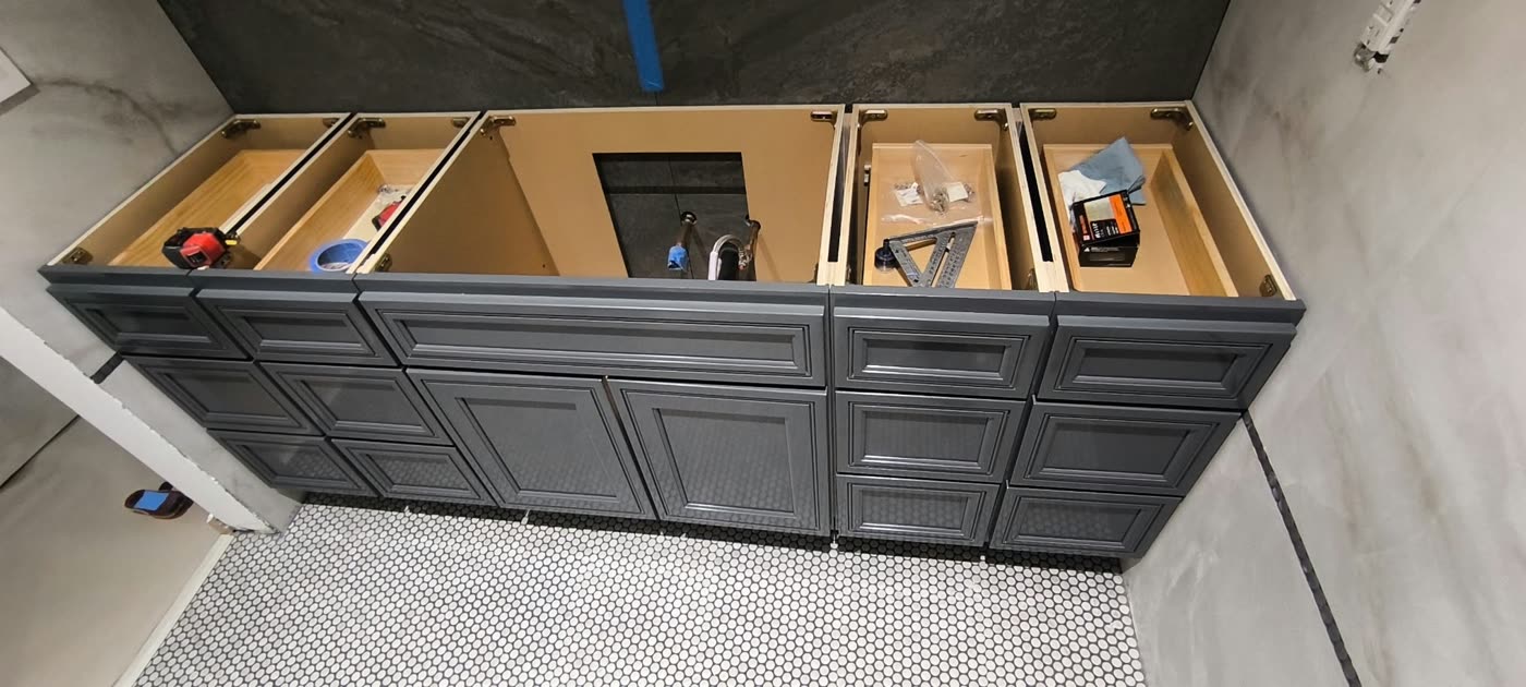 Bathroom remodel in progress: a gray double vanity cabinet being installed on a penny-tile floor — ProRock Remodeling, Bay Area