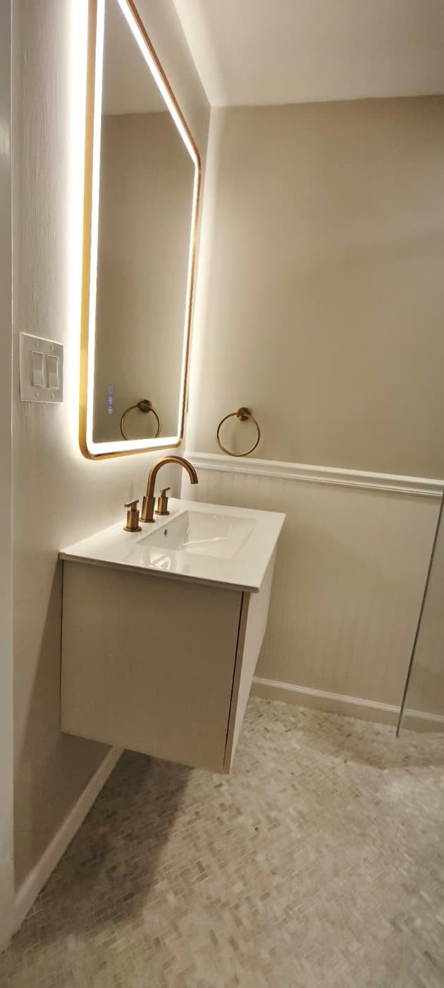 Floating white vanity with a brushed-gold faucet under a backlit mirror, with wainscoting — ProRock Remodeling, Bay Area