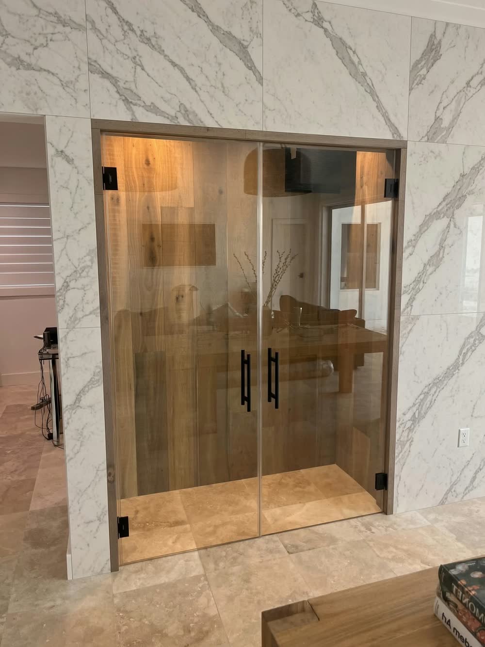 Frameless glass double doors with black handles set into white marble-look tile walls — ProRock Remodeling, Bay Area
