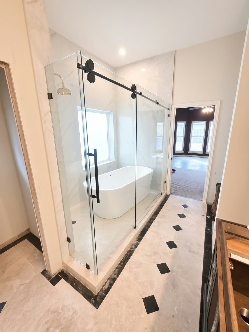 Bathroom with a sliding glass enclosure around a freestanding tub and a tile floor with black diamond accents — ProRock Remodeling, Bay Area