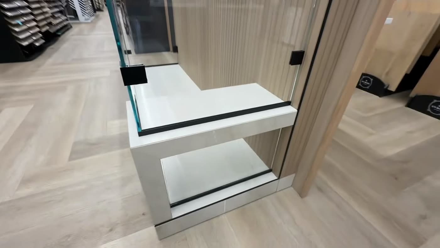 Frameless glass shower panels with a built-in white bench over a herringbone wood-look floor — ProRock Remodeling, Bay Area