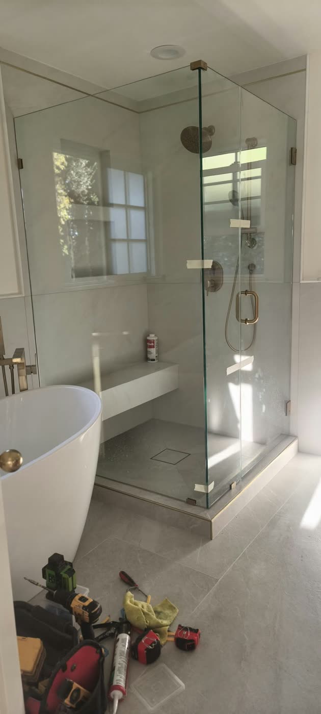Glass shower enclosure being installed next to a freestanding tub, with tools on the floor — ProRock Remodeling, Bay Area
