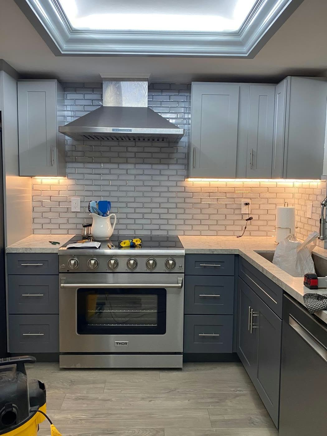 Gray shaker kitchen with white subway tile, a stainless hood and range under a lit tray ceiling — ProRock Remodeling, Bay Area