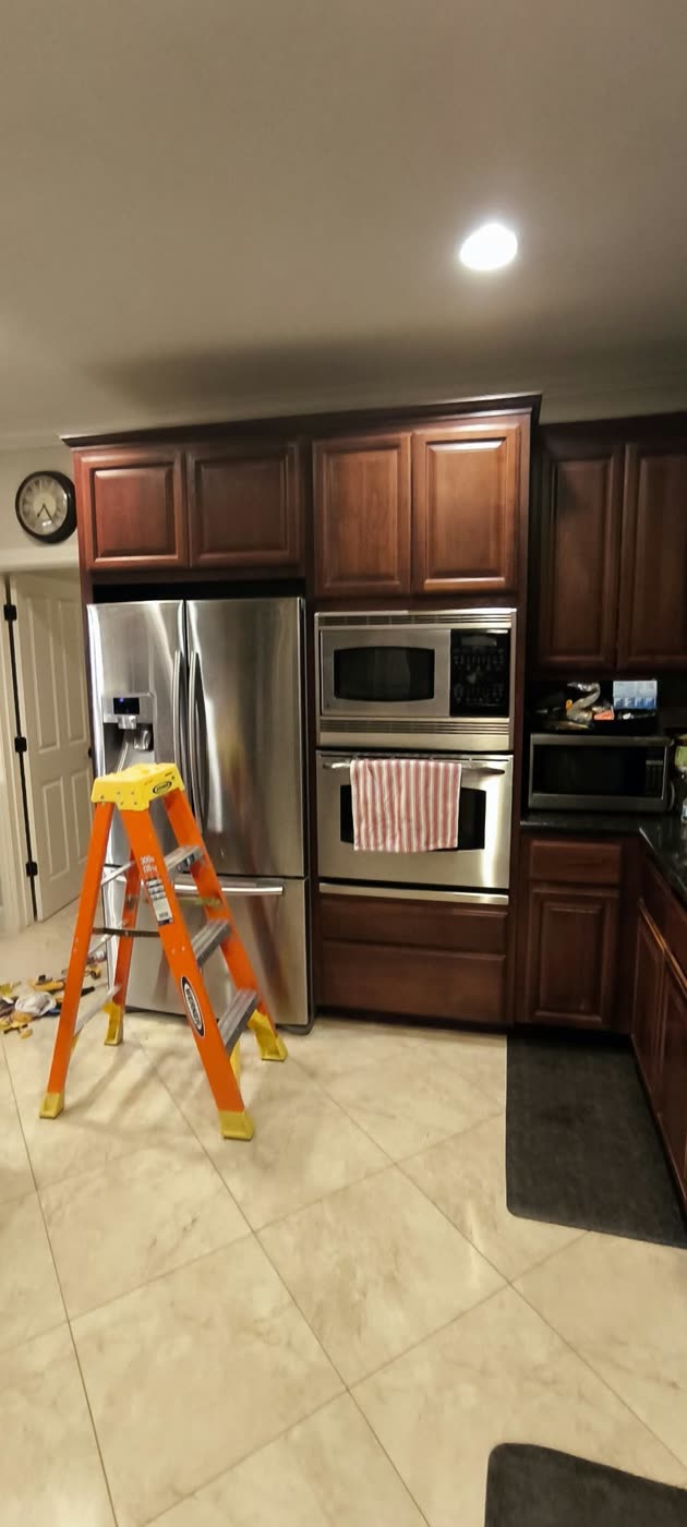 Kitchen before the remodel, with dated cherry cabinets and beige floor tile and a ladder set up for demolition — ProRock Remodeling, Bay Area