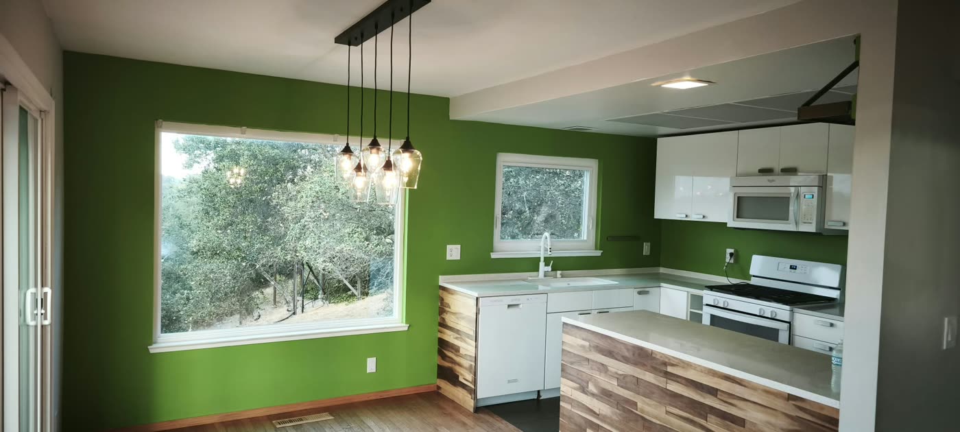 Kitchen and dining area with green accent walls, pendant lights and white cabinets — ProRock Remodeling, Bay Area