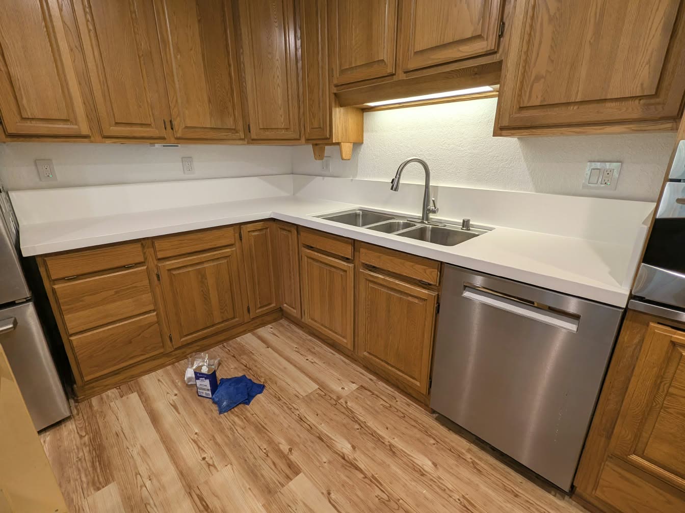 Remodeled kitchen with oak cabinets, white quartz countertops, an undermount double sink and a stainless dishwasher