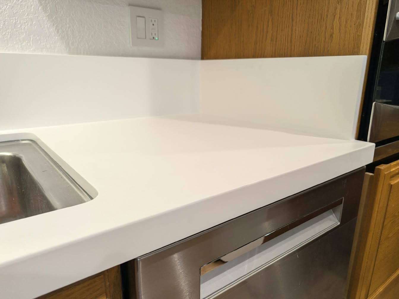 Close-up of a white quartz countertop with a matching backsplash and an undermount stainless sink — ProRock Remodeling, Bay Area