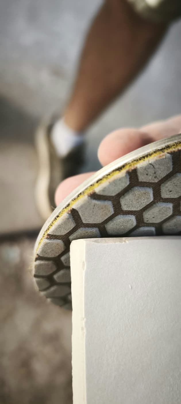Close-up of a diamond polishing pad smoothing the edge of a white stone countertop — ProRock Remodeling, Bay Area